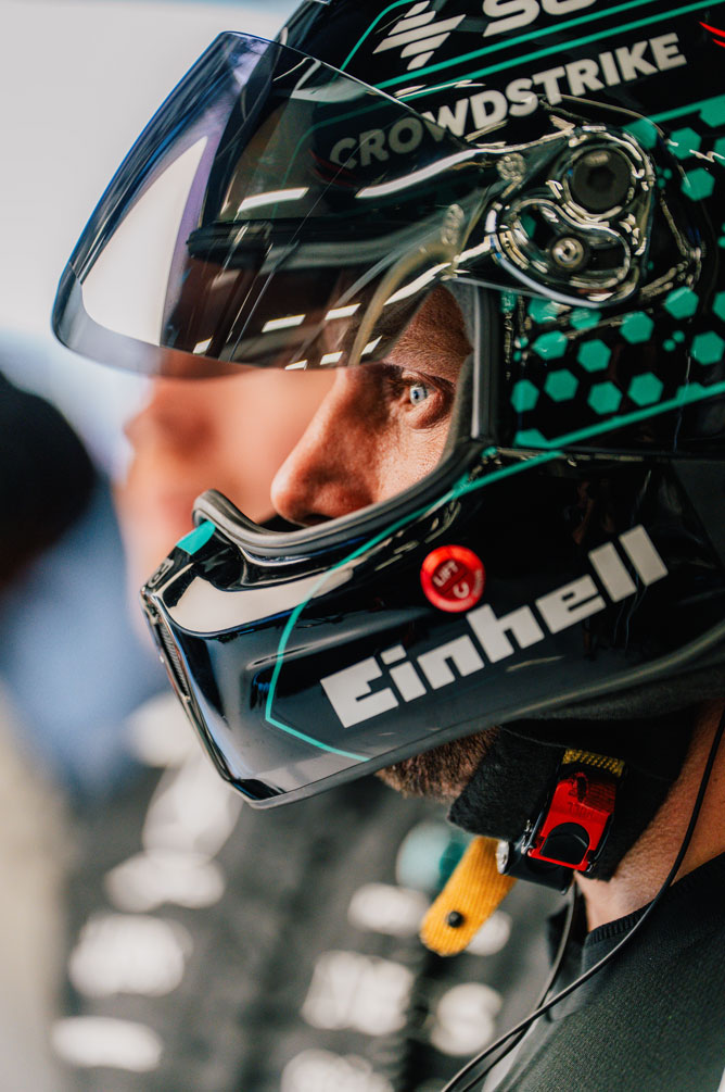 Član ekipe Formule 1 nosi čelado in z zbranostjo gleda vstran.