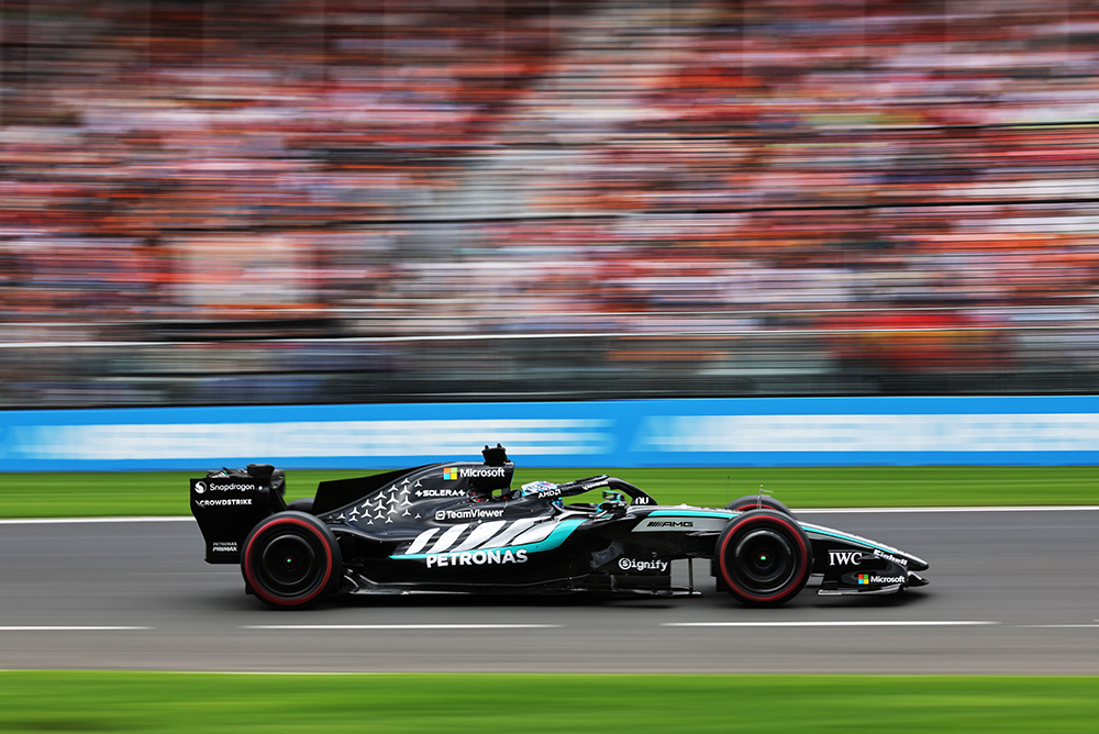 Dirkalnik Formule 1 vozi z veliko hitrostjo po stezi.