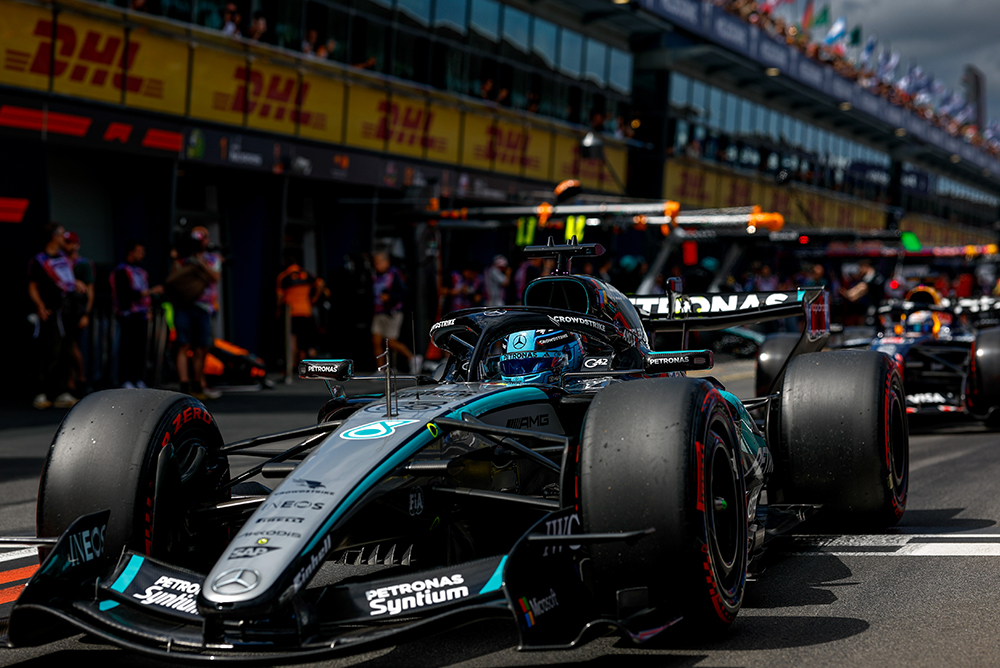 Dirkalnik Formule 1 v pit laneu obdan z ekipo pred startom.