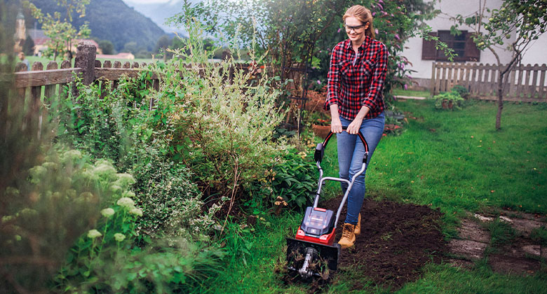 woman working with cordless tiller in the garden