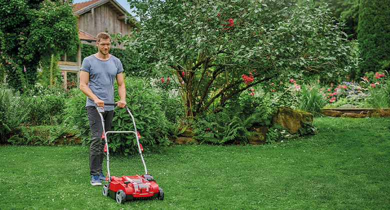 A man scarifying the lawn in his garden with a cordless scarifier.