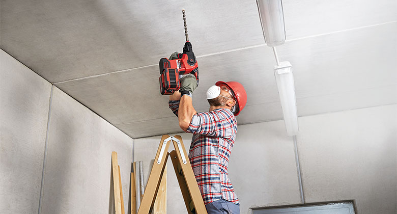 A man working with a cordless rotary hammer
