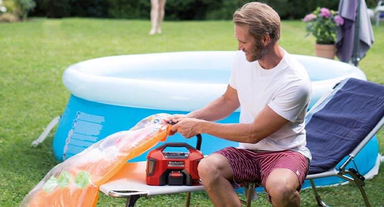 man using a cordless air compressor to inflate an air mattress